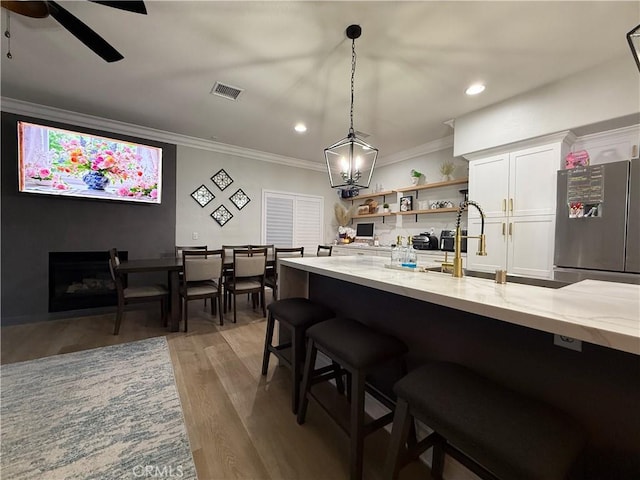 23 Ponte Sonata, Lake Elsinore, CA 92532 - kitchen featuring freestanding refrigerator, open shelves, ornamental molding, light stone countertops, and hanging light fixtures