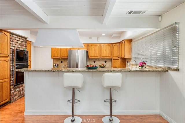 4864 Hersholt Ave, Long Beach, CA 90808 - kitchen featuring black appliances, light wood finished floors, beam ceiling, light stone counters, and tasteful backsplash
