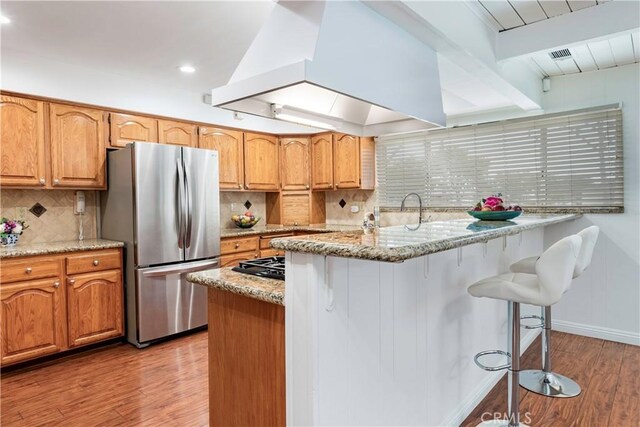 4864 Hersholt Ave, Long Beach, CA 90808 - kitchen with freestanding refrigerator, a breakfast bar area, light wood finished floors, light stone countertops, and recessed lighting