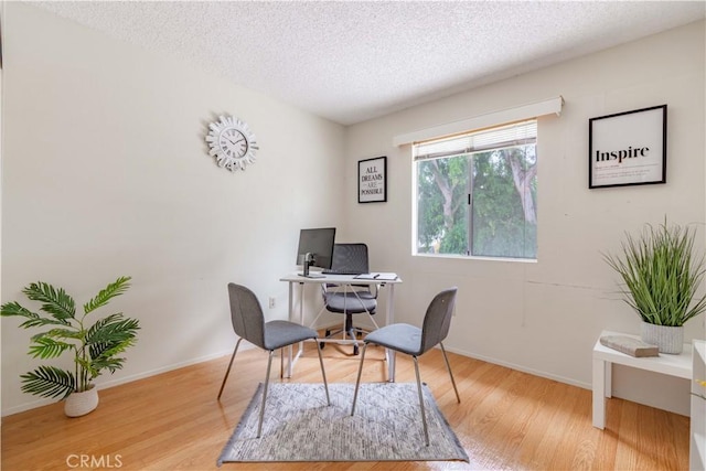 office space featuring wood finished floors, a textured ceiling, and baseboards