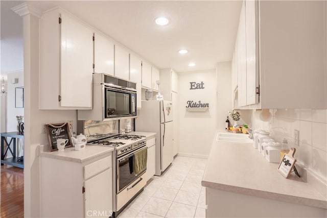kitchen featuring gas range oven, black microwave, a sink, light countertops, and decorative backsplash