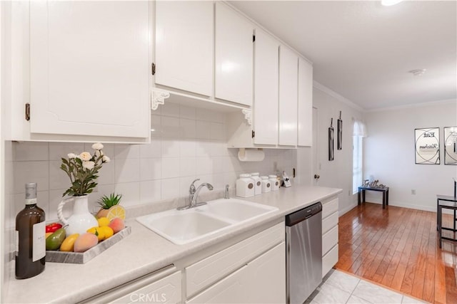 kitchen with dishwashing machine, a sink, white cabinetry, crown molding, and light countertops