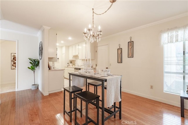 dining space featuring light wood-style flooring, crown molding, a chandelier, and healthy amount of natural light