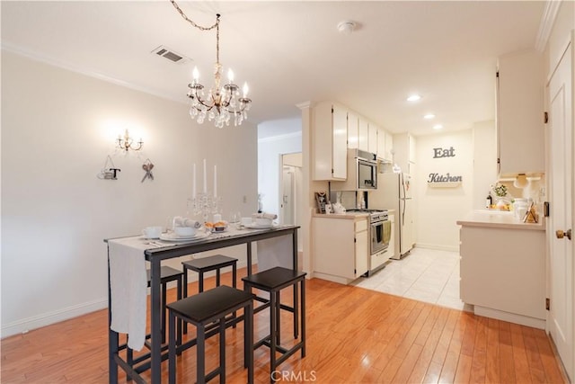 dining area featuring a chandelier, light wood-type flooring, recessed lighting, ornamental molding, and baseboards