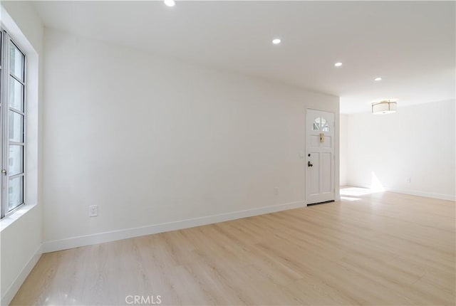 spare room with light wood-type flooring, healthy amount of natural light, recessed lighting, and baseboards