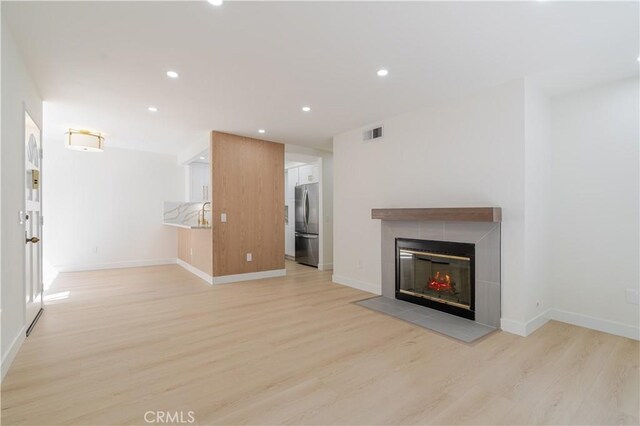 unfurnished living room with light wood-type flooring, a fireplace, recessed lighting, and baseboards
