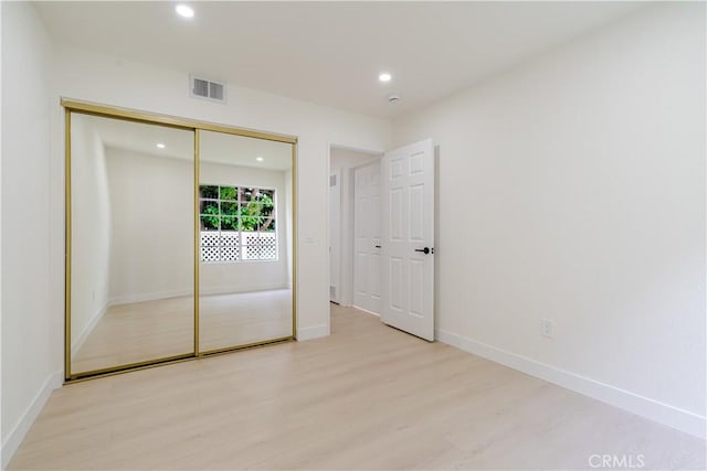 unfurnished bedroom featuring light wood finished floors, recessed lighting, baseboards, and a closet