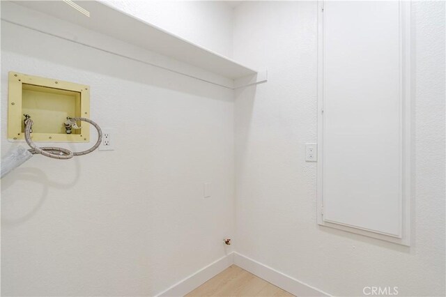 clothes washing area featuring baseboards, light wood finished floors, and gas dryer hookup