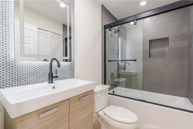 bathroom with toilet, backsplash, combined bath / shower with glass door, and vanity