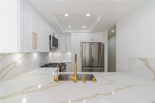 kitchen with stainless steel appliances, white cabinetry, light stone counters, tasteful backsplash, and recessed lighting
