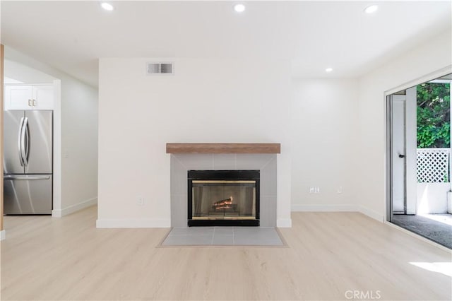 unfurnished living room with light wood finished floors, baseboards, recessed lighting, and a fireplace