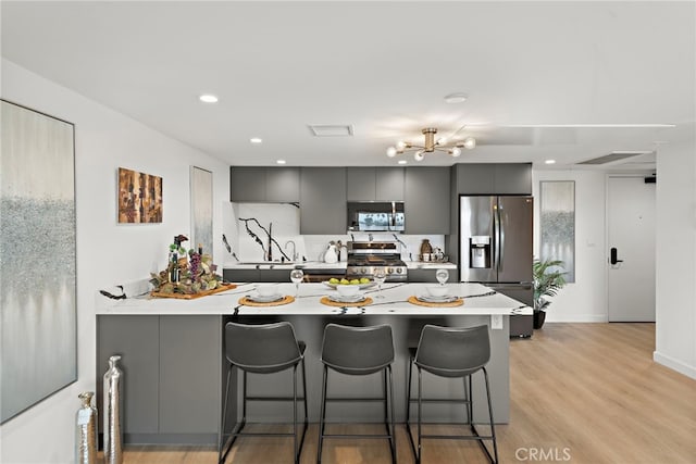 321 S Oxford Ave Unit 603, Los Angeles, CA 90020 - kitchen with stainless steel appliances, a breakfast bar, a peninsula, light countertops, and light wood-style floors