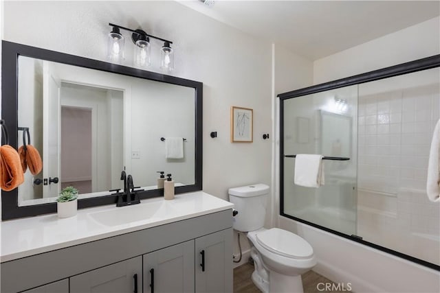 bathroom featuring toilet, vanity, and enclosed tub / shower combo