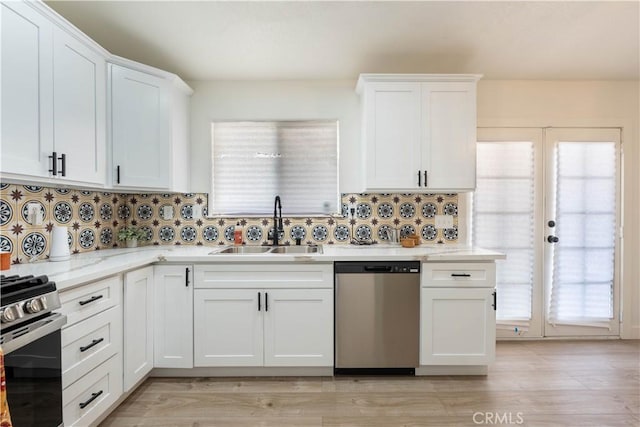kitchen featuring appliances with stainless steel finishes, a sink, white cabinetry, and decorative backsplash
