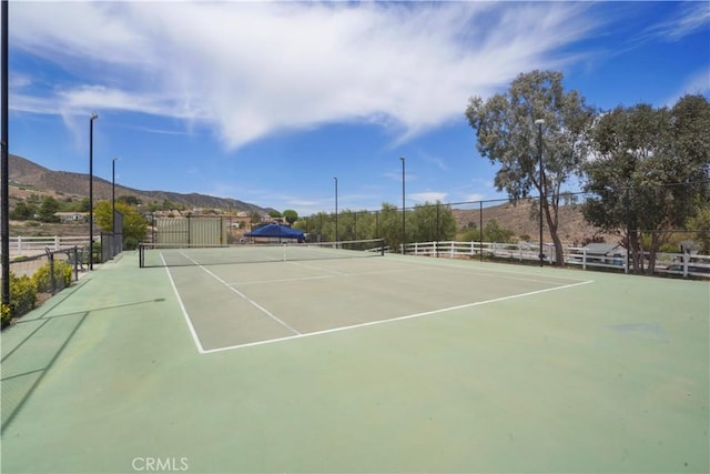 view of tennis court featuring fence and a mountain view