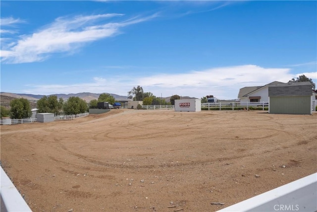 view of yard featuring fence, a mountain view, and an outdoor riding arena