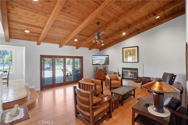 living area featuring wooden ceiling, light wood-style floors, a glass covered fireplace, a ceiling fan, and baseboards