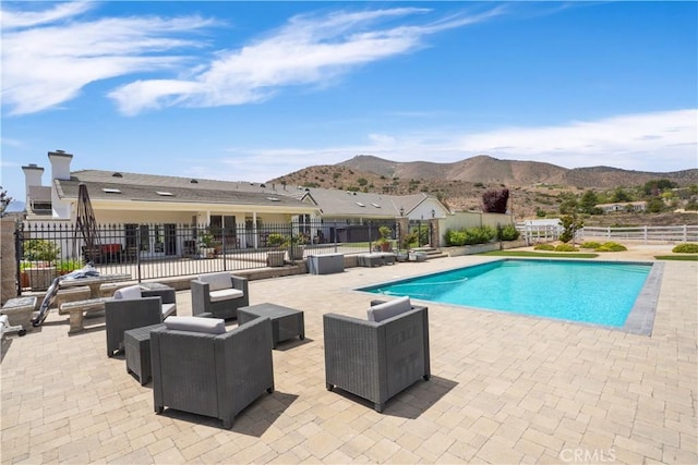 view of swimming pool featuring a mountain view, a patio area, and fence