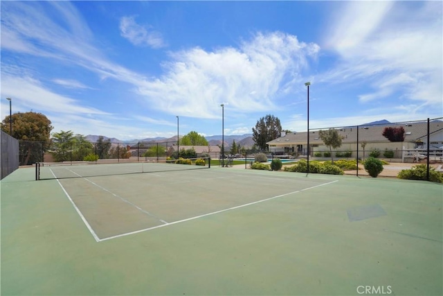 view of tennis court with fence, a mountain view, and community basketball court