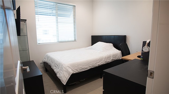 carpeted bedroom with multiple windows and a desk