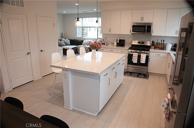 kitchen with stainless steel appliances, a breakfast bar area, light countertops, light wood-type flooring, and recessed lighting