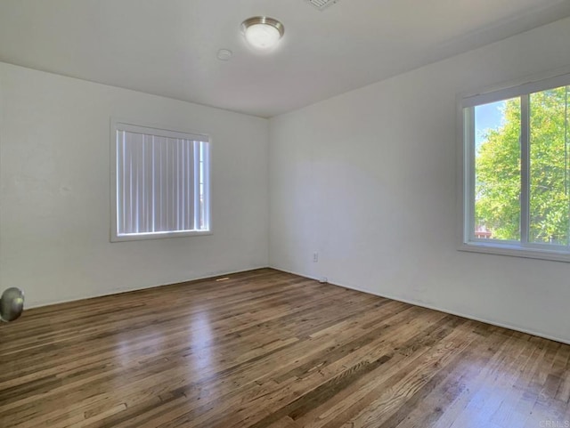 unfurnished room featuring healthy amount of natural light and wood finished floors
