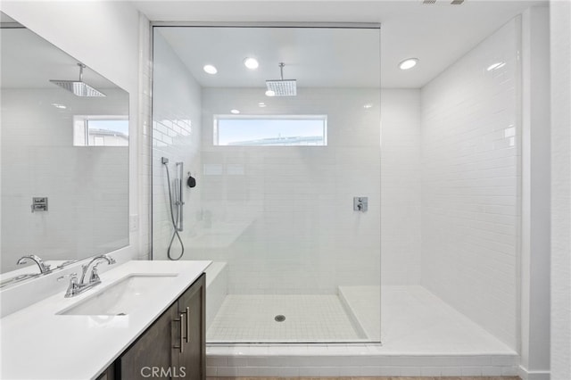 bathroom featuring a tile shower, vanity, and recessed lighting