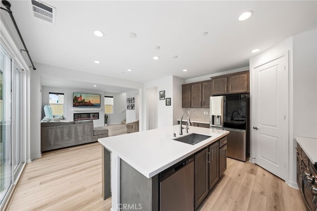 kitchen with a sink, appliances with stainless steel finishes, light wood-style flooring, light countertops, and recessed lighting