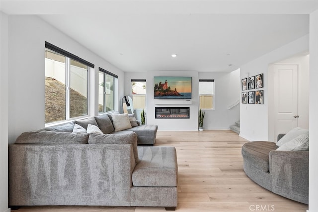 living area with light wood-style floors, recessed lighting, a glass covered fireplace, and baseboards