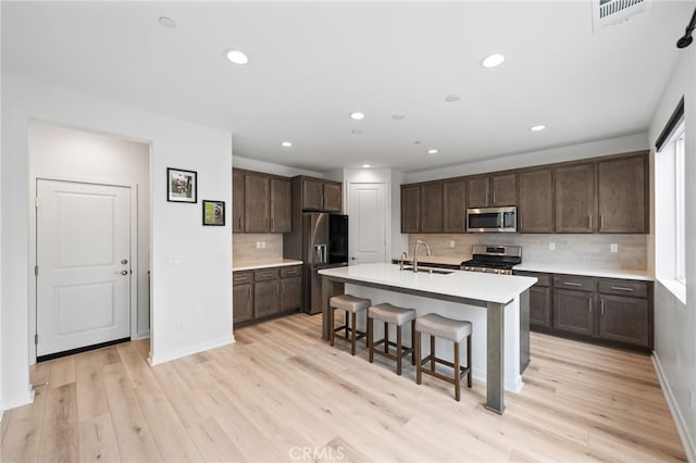 32182 Penstemon Way, Temecula, CA 92591 - kitchen with stainless steel appliances, a sink, dark brown cabinets, a breakfast bar, and decorative backsplash