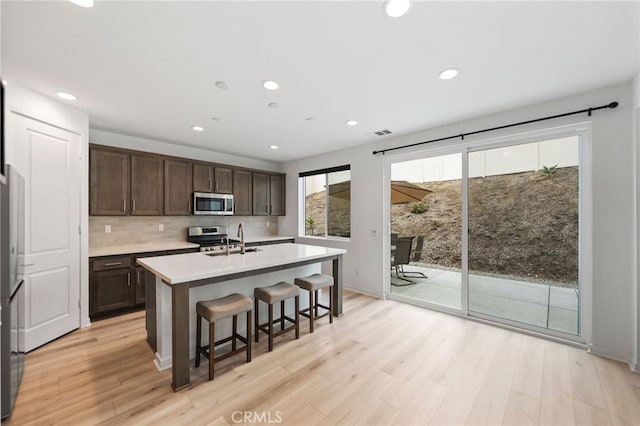 32182 Penstemon Way, Temecula, CA 92591 - kitchen with appliances with stainless steel finishes, a sink, dark brown cabinetry, an island with sink, and light countertops