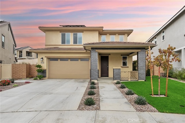 prairie-style home with a porch, stucco siding, solar panels, and driveway