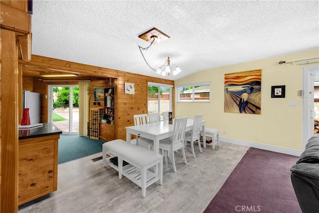1005 E Woodland Ln, Glendora, CA 91741 - dining space featuring a chandelier, vaulted ceiling, wood walls, a textured ceiling, and baseboards