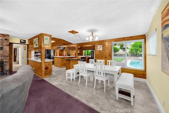 1005 E Woodland Ln, Glendora, CA 91741 - dining space featuring a textured ceiling, a chandelier, wooden walls, light wood-type flooring, and baseboards