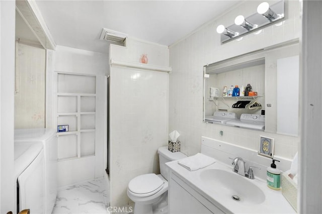 1005 E Woodland Ln, Glendora, CA 91741 - full bathroom with washing machine and dryer, marble look tiles, vanity, and toilet