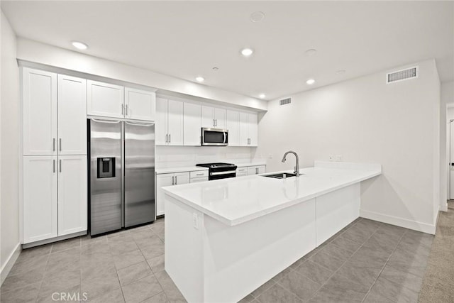 16321 Dawn Way Unit 108, Tustin, CA 92782 - kitchen with stainless steel appliances, a sink, a peninsula, light tile patterned floors, and white cabinetry