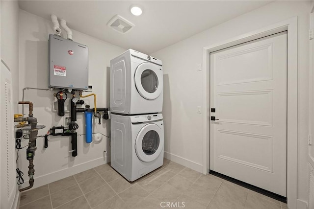 16321 Dawn Way Unit 108, Tustin, CA 92782 - laundry room with stacked washer and clothes dryer, tankless water heater, baseboards, and light tile patterned flooring