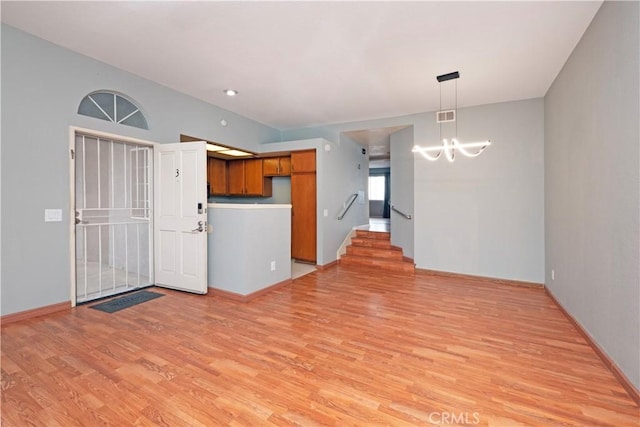 776 E San Bernardino Rd Unit 3, Covina, CA 91723 - unfurnished living room with a chandelier, light wood-style floors, baseboards, and stairway