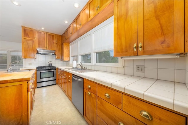 kitchen with stainless steel appliances, under cabinet range hood, a sink, butcher block counters, and recessed lighting