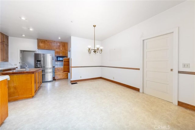 kitchen with stainless steel fridge with ice dispenser, a sink, a chandelier, black microwave, and brown cabinets