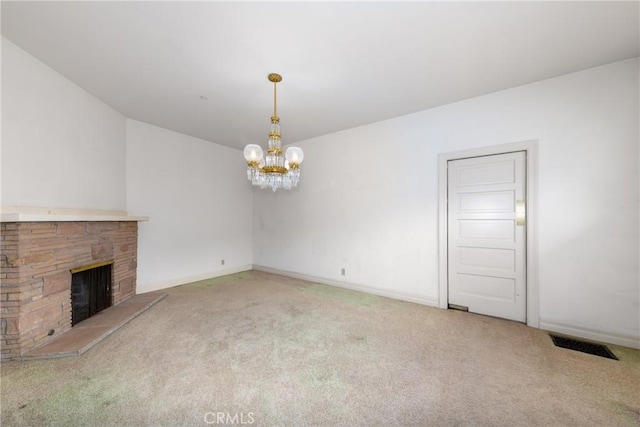 unfurnished living room with carpet floors, a chandelier, a fireplace, and baseboards