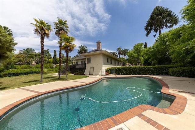 outdoor pool with stairway, a yard, and a wooden deck