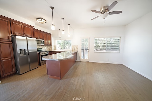 kitchen featuring appliances with stainless steel finishes, a peninsula, light wood-style floors, and decorative backsplash