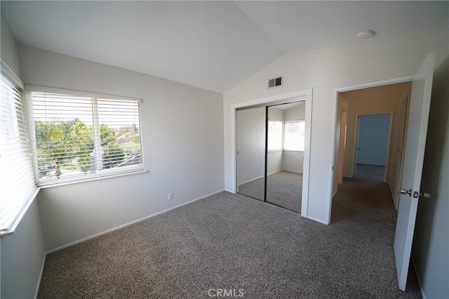 unfurnished bedroom featuring carpet, lofted ceiling, a closet, and baseboards