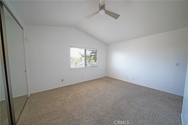 unfurnished bedroom with carpet floors, lofted ceiling, a ceiling fan, a closet, and baseboards
