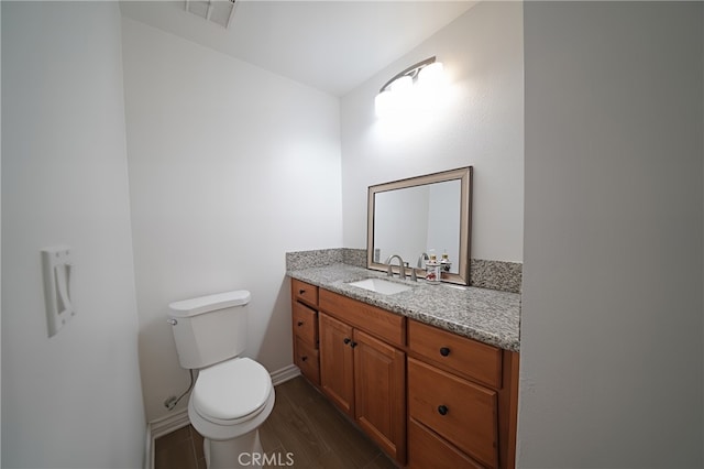 bathroom with wood finished floors, toilet, vanity, and baseboards