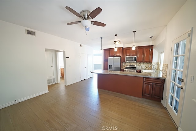 kitchen featuring stainless steel appliances, a peninsula, tasteful backsplash, ceiling fan, and wood finished floors