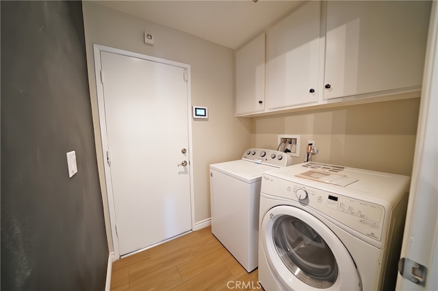 washroom with cabinet space, washer and dryer, light wood-type flooring, and baseboards