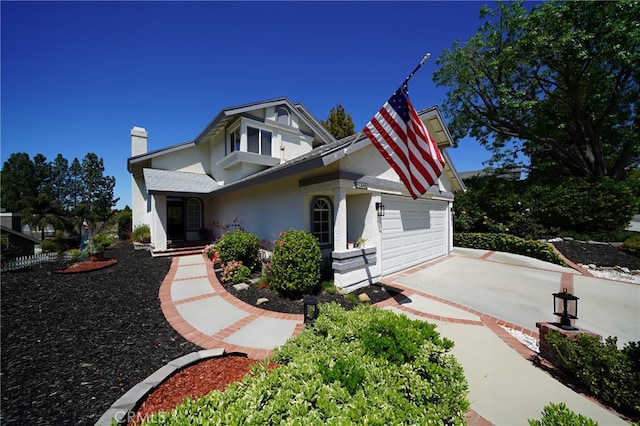 view of front of property featuring concrete driveway, a garage, stucco siding, and a chimney