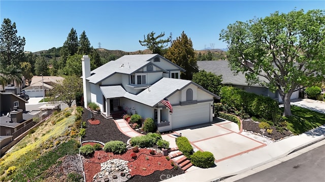 view of front facade featuring a garage, a chimney, concrete driveway, and stucco siding